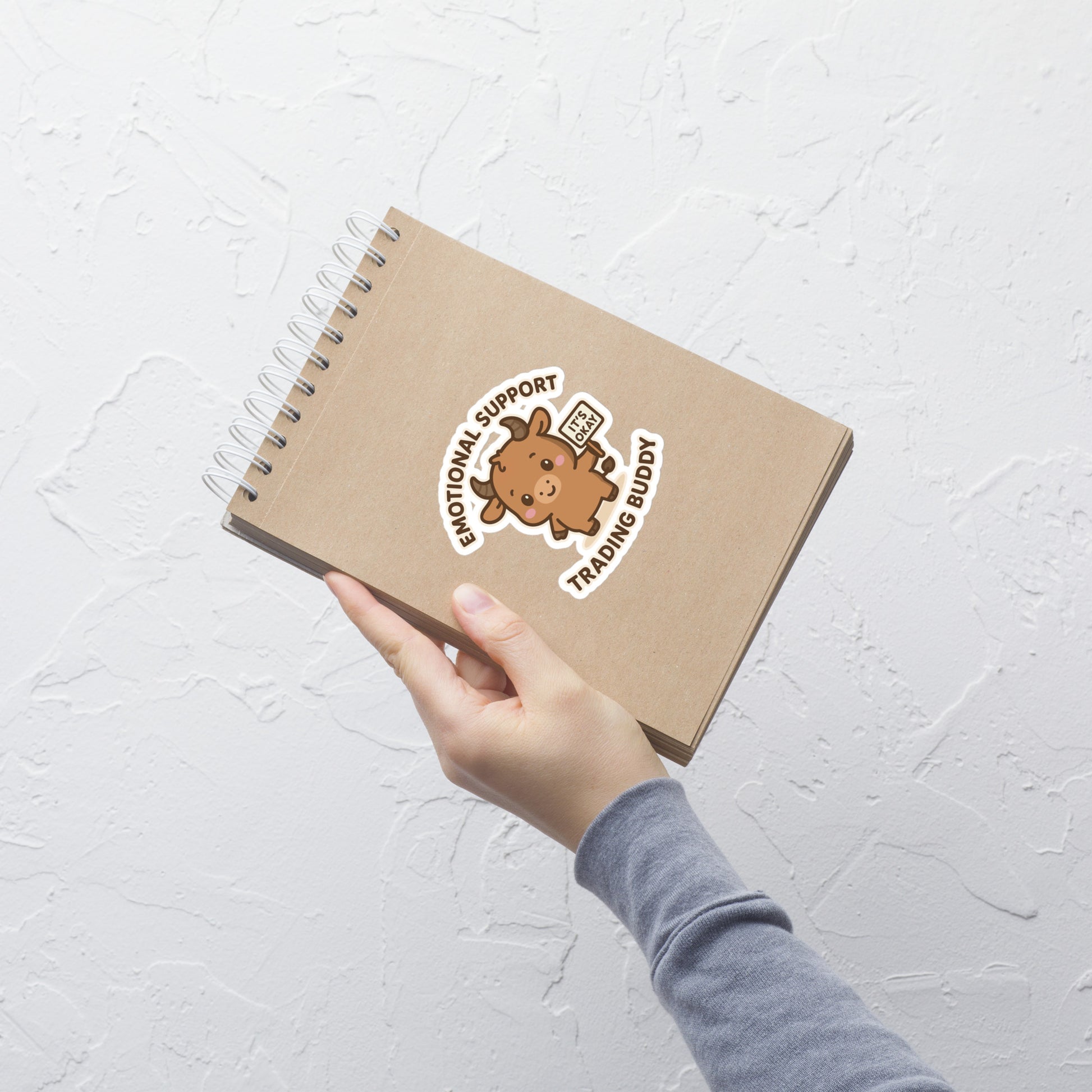 Notebook with a Stock Market Trading bull sticker on a textured white surface