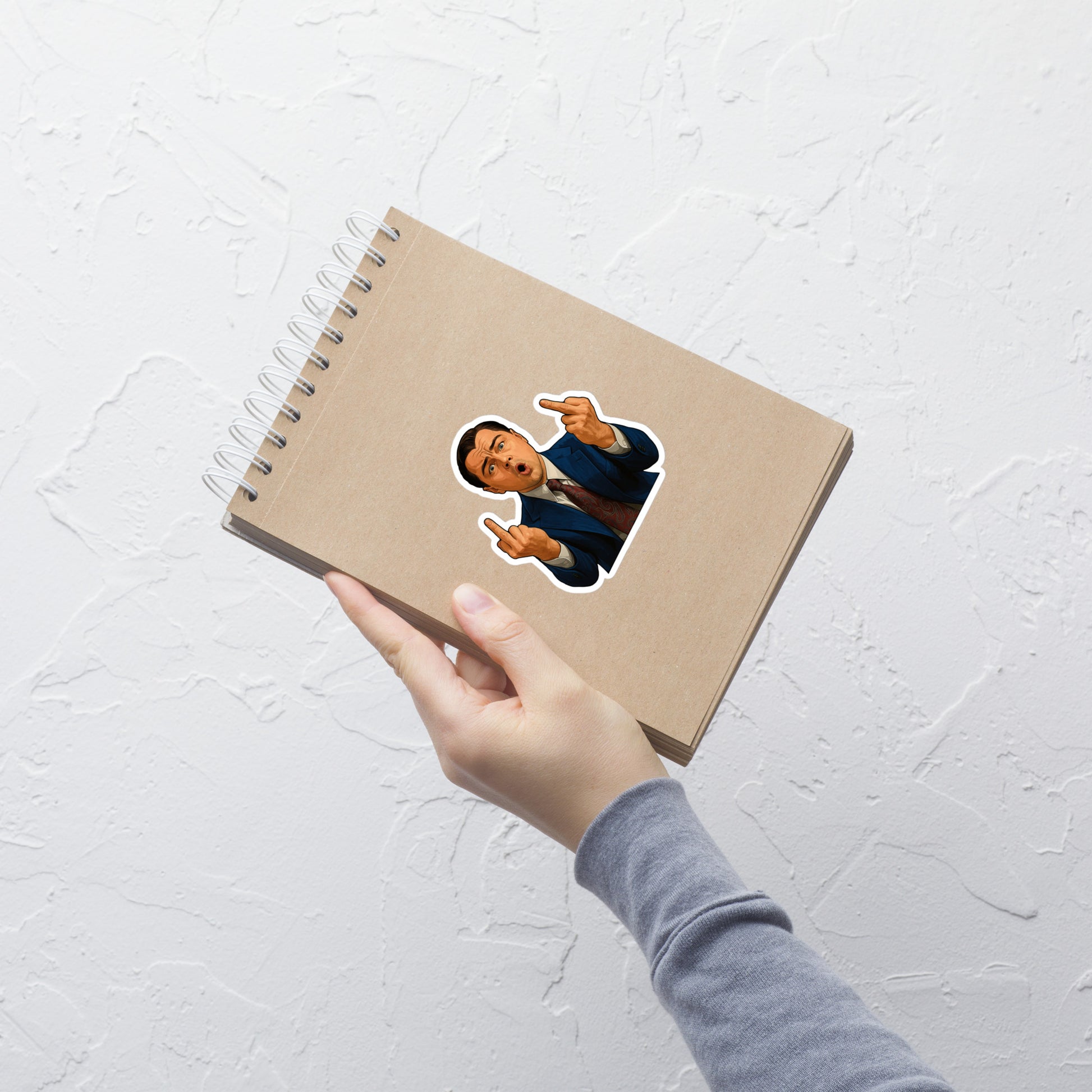 Notebook with a sticker of Wolf of Wall Street on a white textured surface